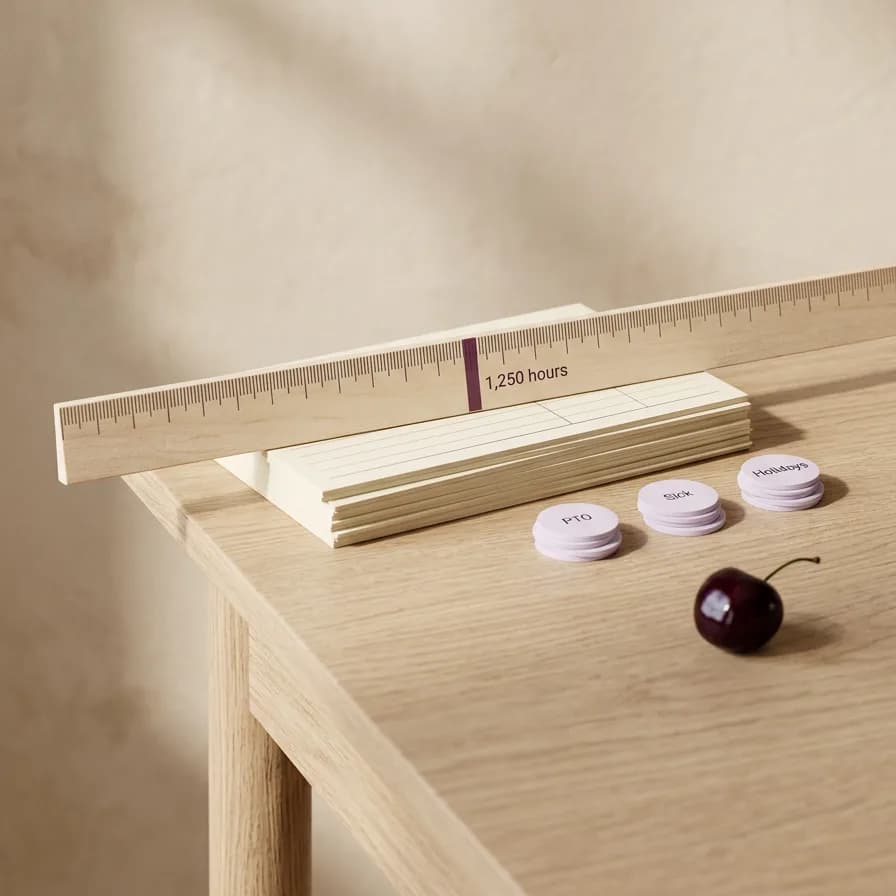 A ruler laid across a stack of timesheets, with a mark at 1,250 and small piles of paid days set aside from the count